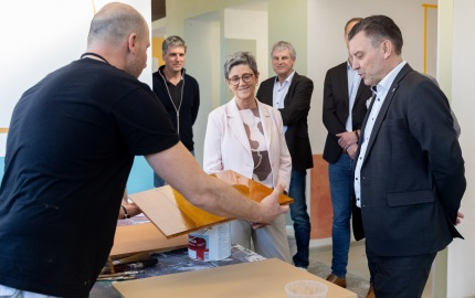 Ausbilder im Malerbereich erklärt Landrat Schröder und Geschäftsführerin Barbara Klink die Oberflächenbehandlung von Holz