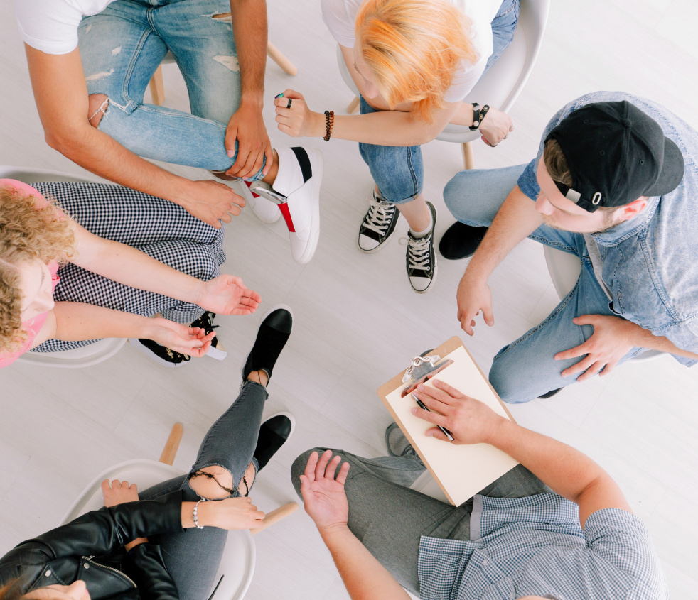 Sechs Personen sitzen im Kreis und diskutieren. Die Personen sind von oben zu sehen.