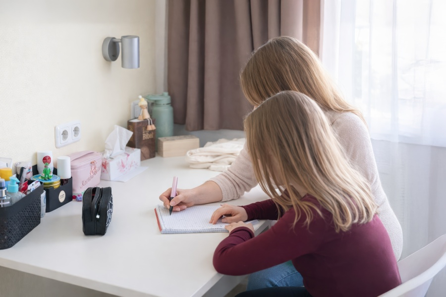 Eine junge Frau sitzt an ihrem Schreibtisch und arbeitet konzentriert. Sie wird unterstützt von einer Betreuerin