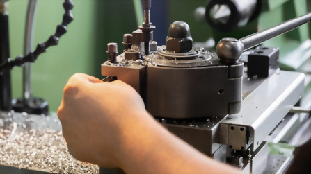 Hand an einer Maschine bei der Metallbearbeitung in der Ausbildungswerkstatt.