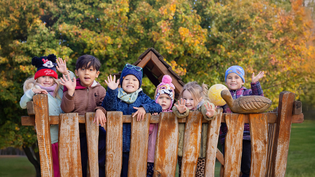 Kindergartenkinder Arche Kolping auf dem Au&szlig;engel&auml;nde winken in Kamera 