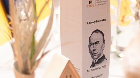 Tischdekoration beim Kolping Gedenktag mit Programmheft und Keramikhaus.