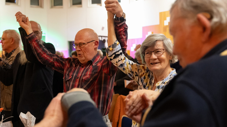 G&auml;ste feiern, nehmen sich bei den H&auml;nden und heben die Arme hoch