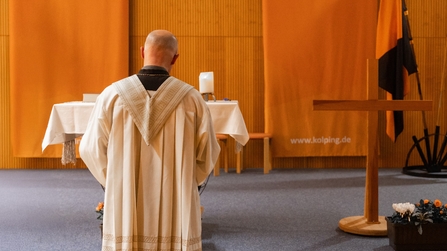 Pfarrer Hansch steht mit dem R&uuml;cken zu G&auml;sten und betet 