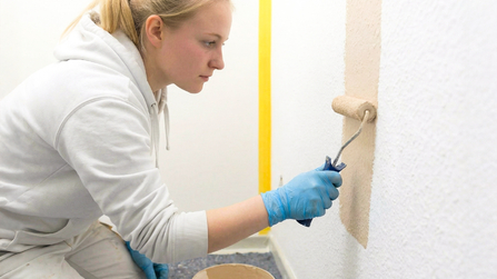Auszubildende bemalt eine Wand 