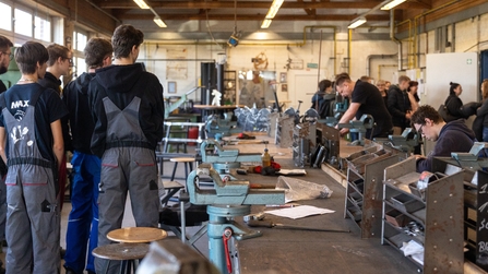 Auszubildende und Besucher stehen in der Metallwerkstatt