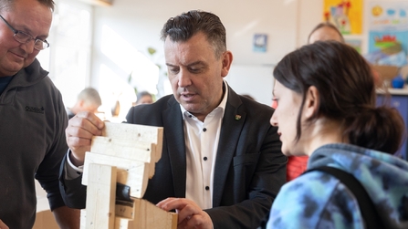Teilnehmende der Inklusionswerkstatt erkl&auml;ren Mann den Bau eines Werkst&uuml;cks