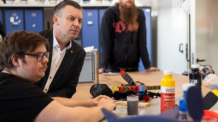 Mitarbeiter der Inklusionswerkstatt zeigen einem Mann ihre Arbeit