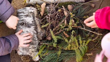 Kinderh&auml;nde f&uuml;gen Naturmaterialien zu einer Landschaft zusammen